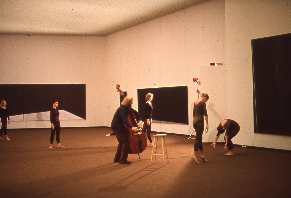 Flere musikere og dansere i et utstillingsrom med malerier hengende på de hvite veggene i bakgrunnen. Foto.