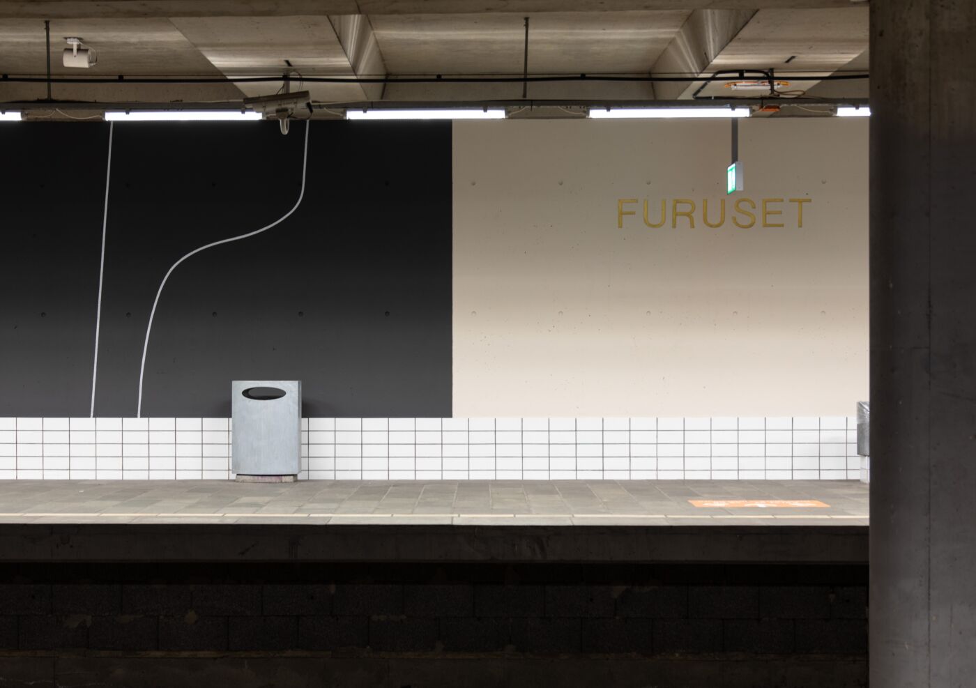 Foto av en t-baneperrong med veggmaleri og teksten "Furuset" skrevet på veggen.