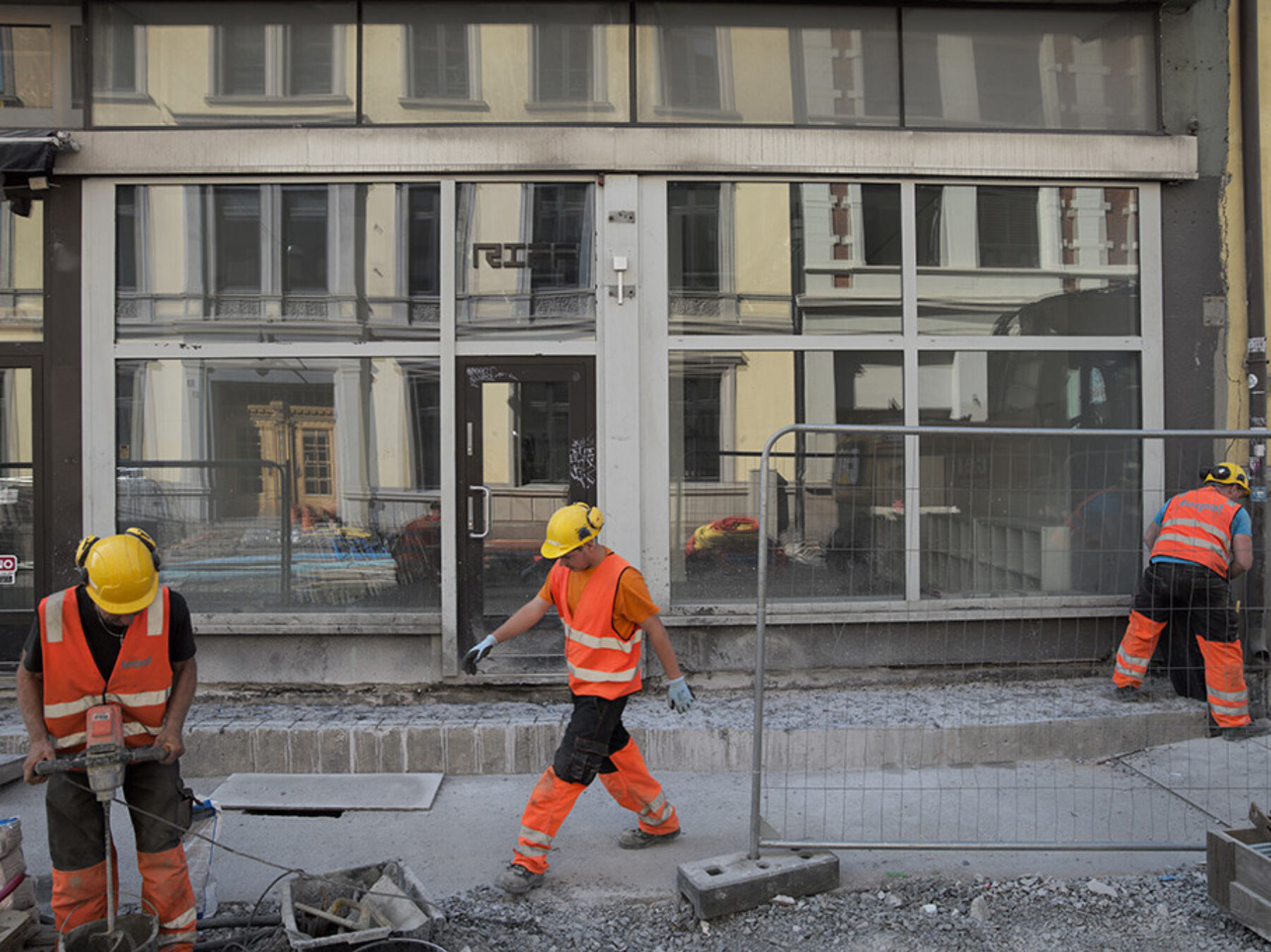 Bilde av anleggsarbeidere i en gate, Et kontorbygg i bakgrunnen. Foto