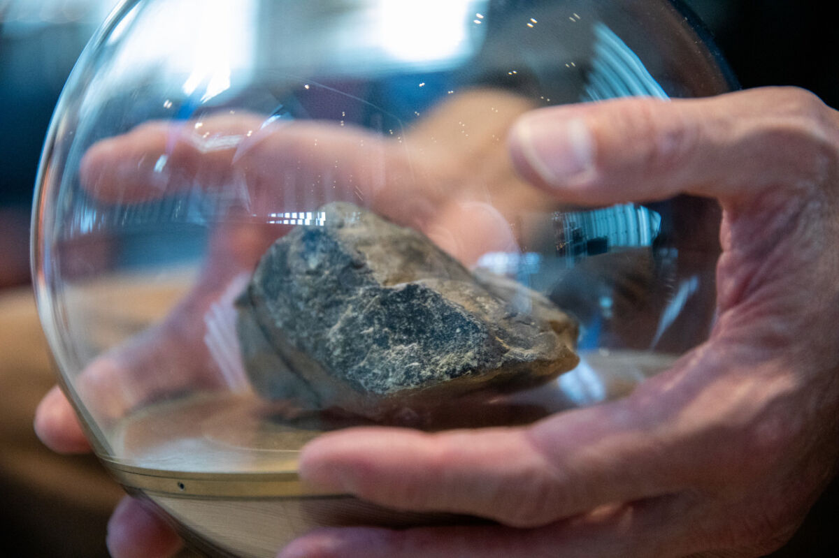 To hender holder i en glasskule med en stein inni. Foto.