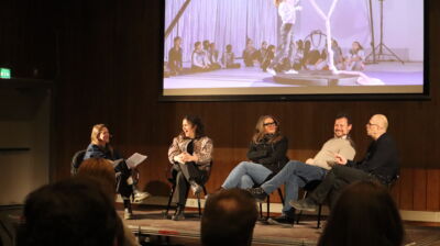 Foto av fem personer sittende i en samtale på en scene.