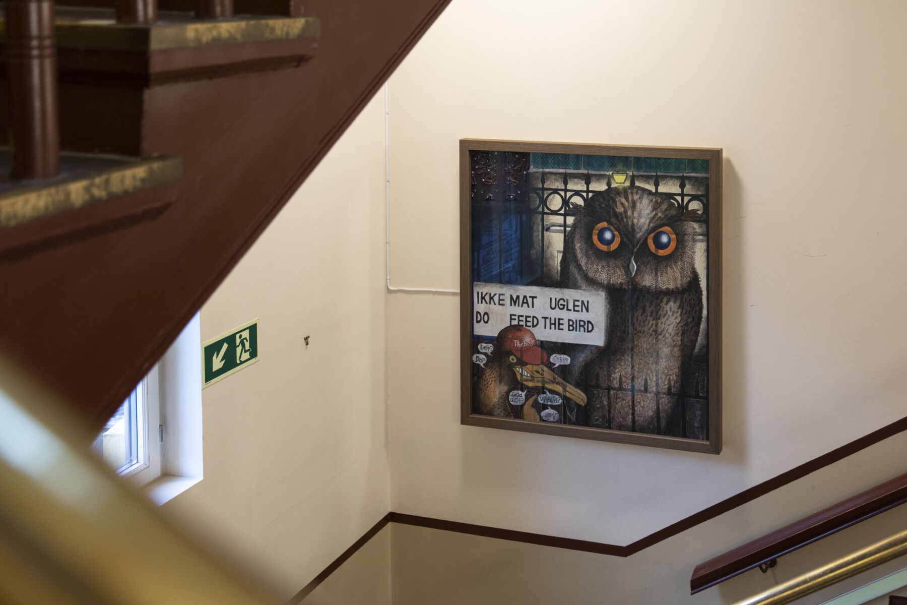 Maleri av en ugle i utemiljø. Maleriet henger i en trappegang. Foto.