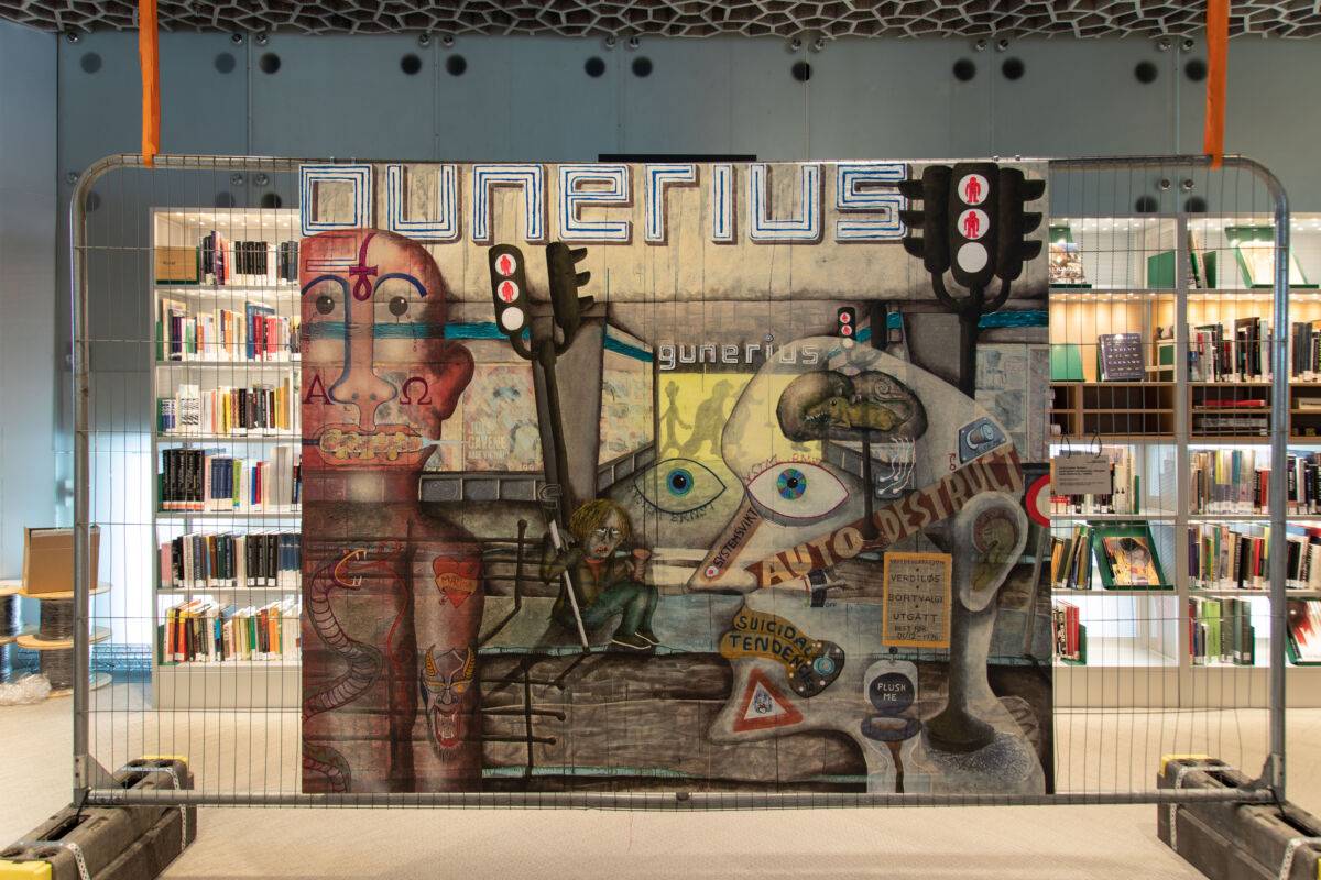 Maleri av menneskelige figurer som henger på et arbeidsgjerde i et bibliotek. Foto.