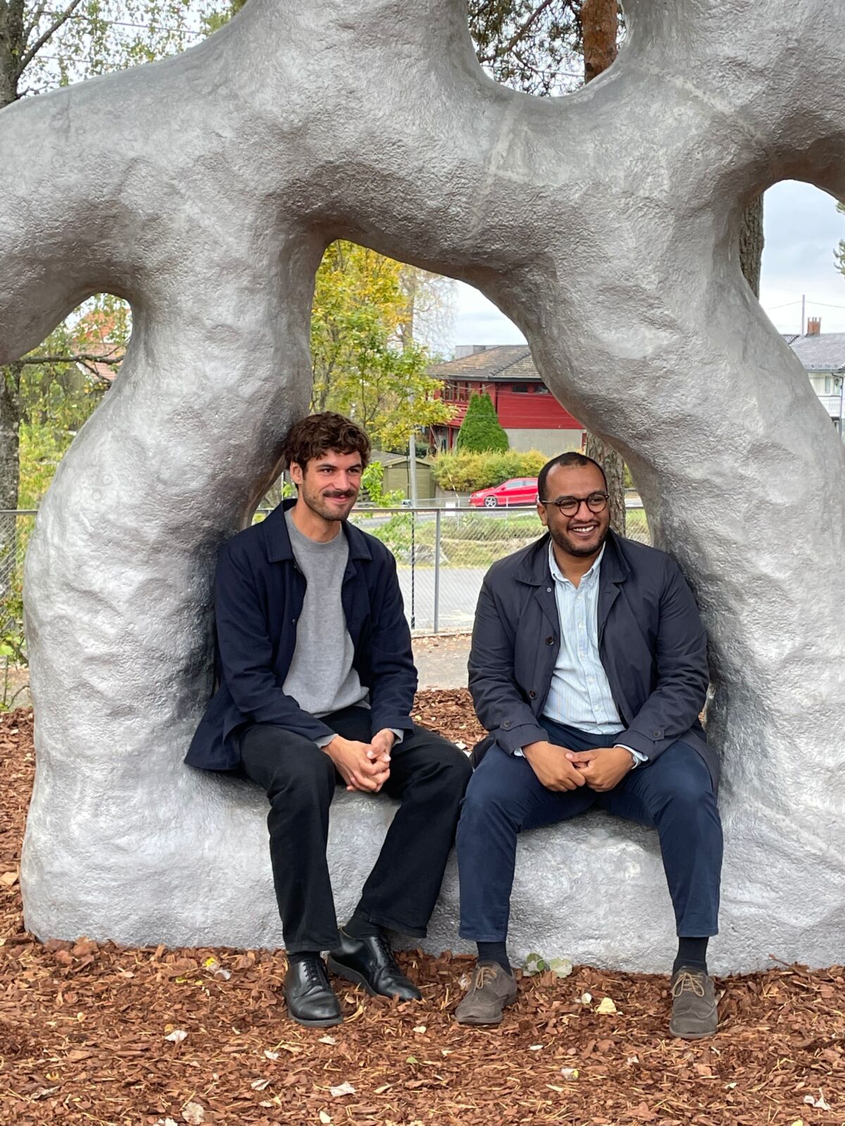 To personer sitter sammen inne i en lysgrå skulptur. Foto.