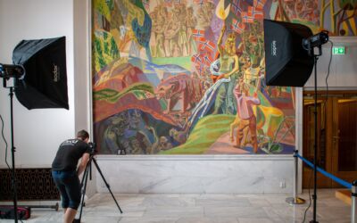 Person fotograferer muralmaleri i Oslo rådhus. Foto.