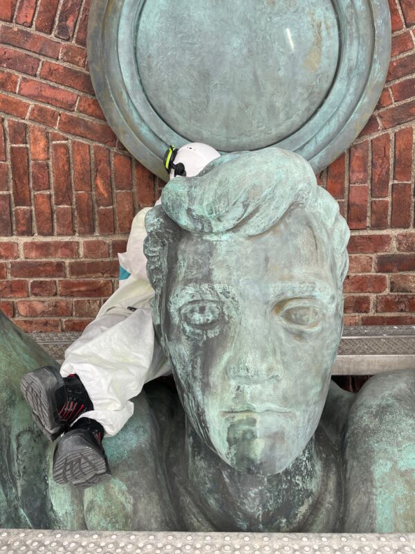 Foto av person som konserverer hodet på en skulptur.