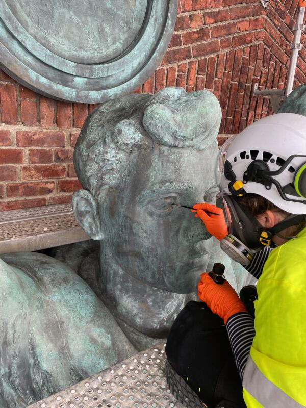 Foto av person som konserverer hodet på en skulptur.