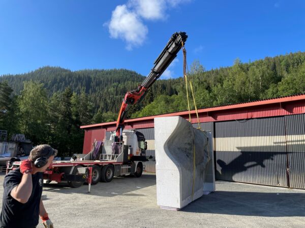 Foto av at en skulptur løftes av en lift utendørs.