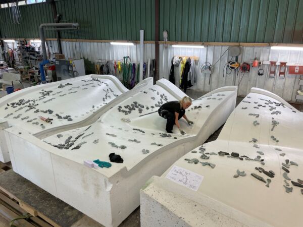 Foto av person som står og jobber på en svær, flat skulptur.