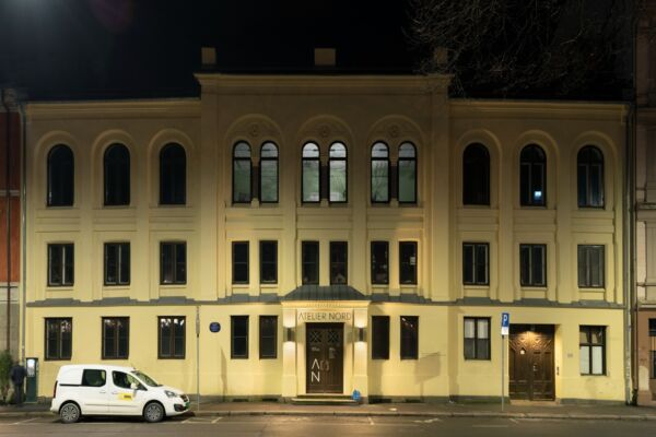 En gul murbygning med en bil foran. Foto.