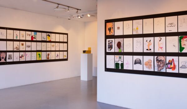 Utstillingslokale med mange tegninger hengt opp på veggene. Foto.