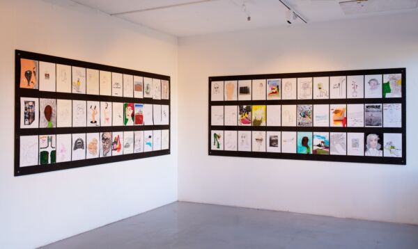 Utstillingslokale med mange tegninger hengt opp på veggene. Foto.