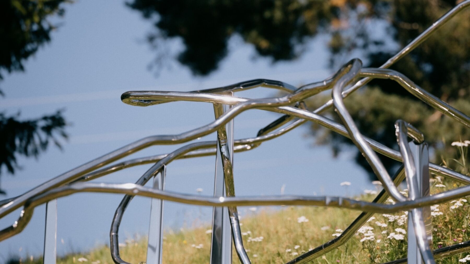 En abstrakt metallskulptur i en blomstereng. Fotografi.