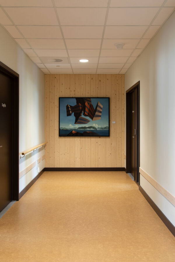 Maleri av Adolph Denis Horn henger på en panelvegg i enden av en gang